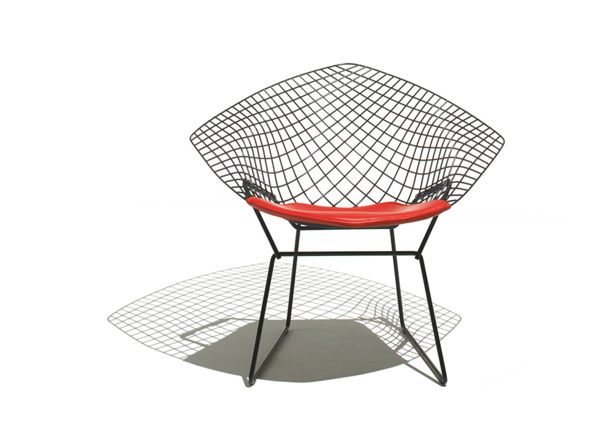 The Bertoia Diamond Chair in a bright, airy setting, showcasing its transparent wire structure.