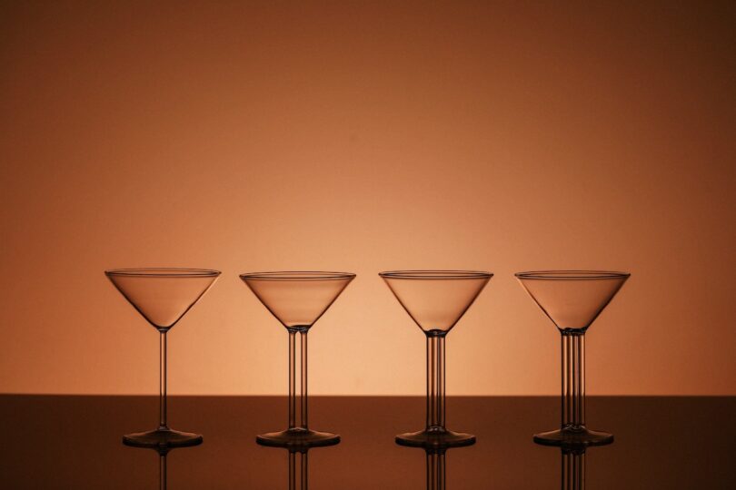 Four empty martini glasses lined up, showing the distinct vertical lines on the stems used for guest identification.