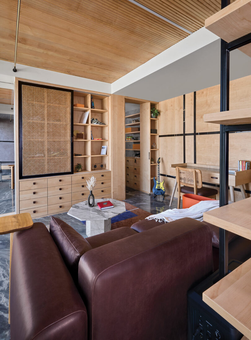 Living area with custom wooden shelving, leather furniture, and textured wall panels.