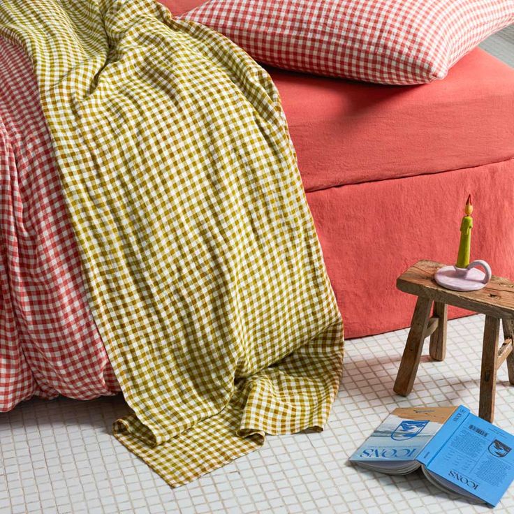 Colorful red and green gingham bedding in a rustic room with a coral bed frame and tiled floor.