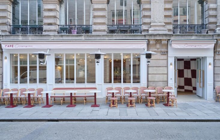 Exterior view of Cafe Compagnon in Paris with bistro chairs and checkered curtains.
