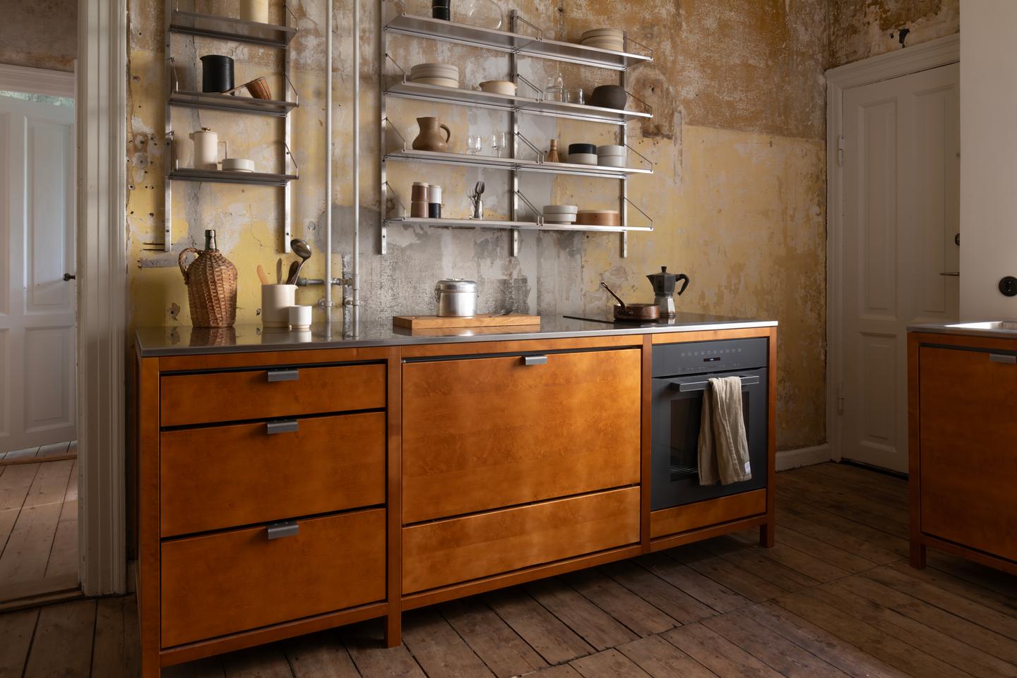 Industrial-style kitchen with stainless steel countertops and warm wooden cabinets.