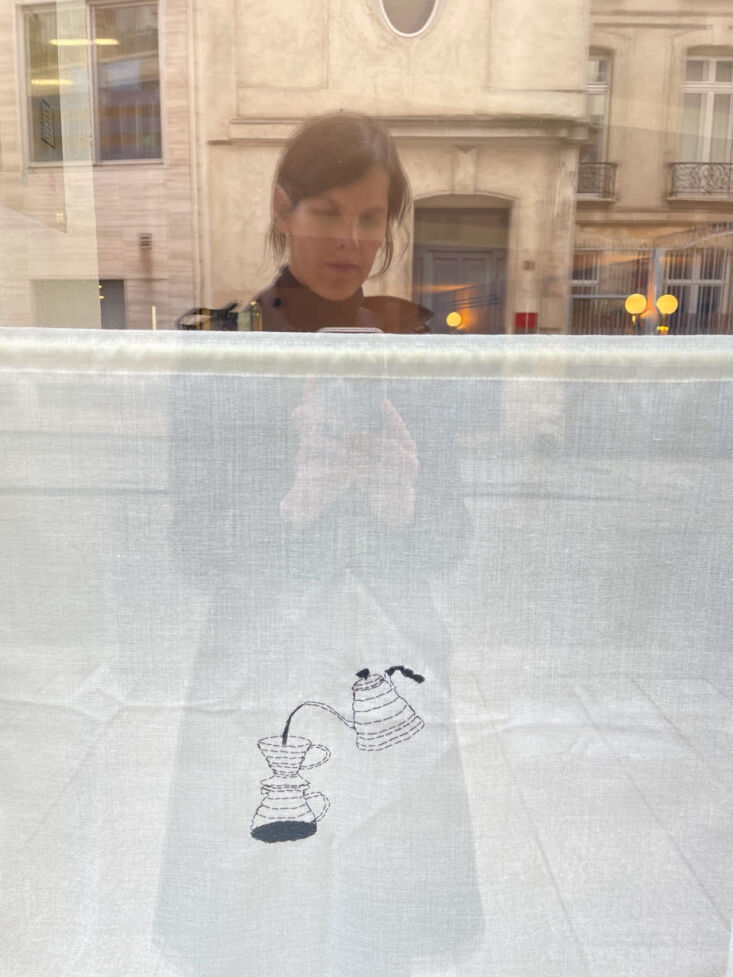 Linen curtains with small embroidered icons related to coffee making.