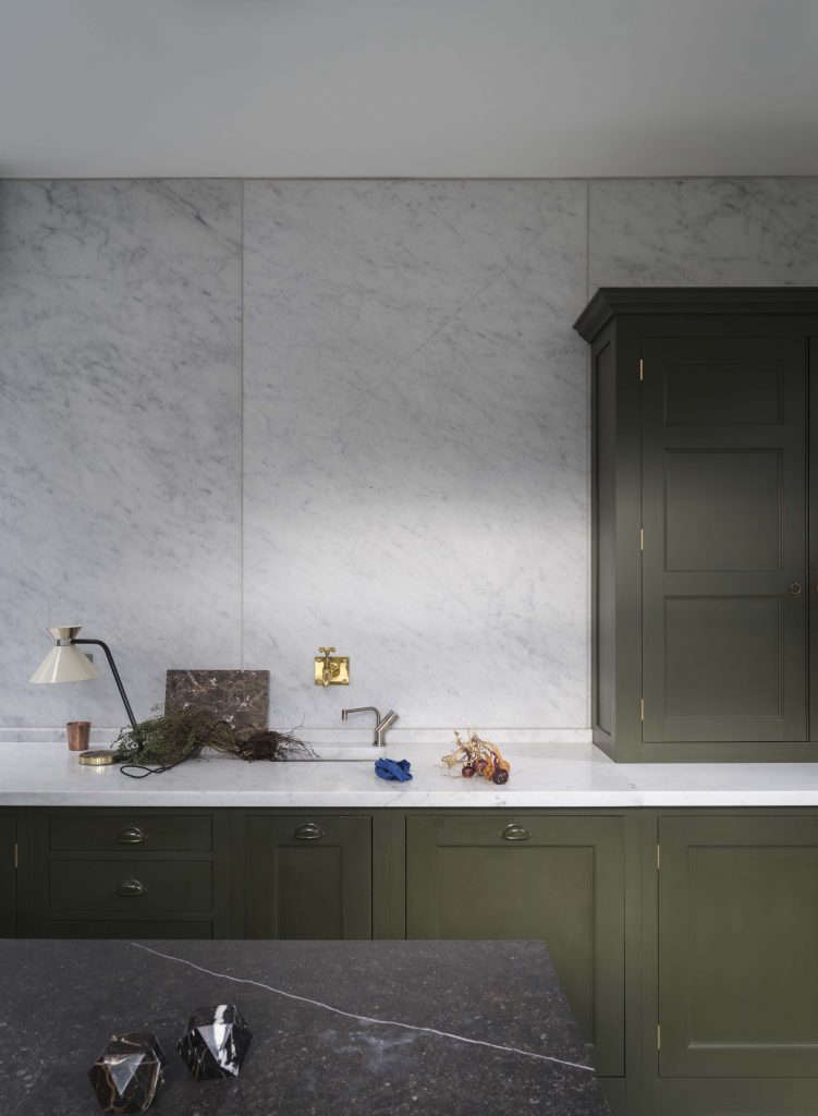 Modern army green Shaker cabinets with a white marble backsplash and dark stone countertops.