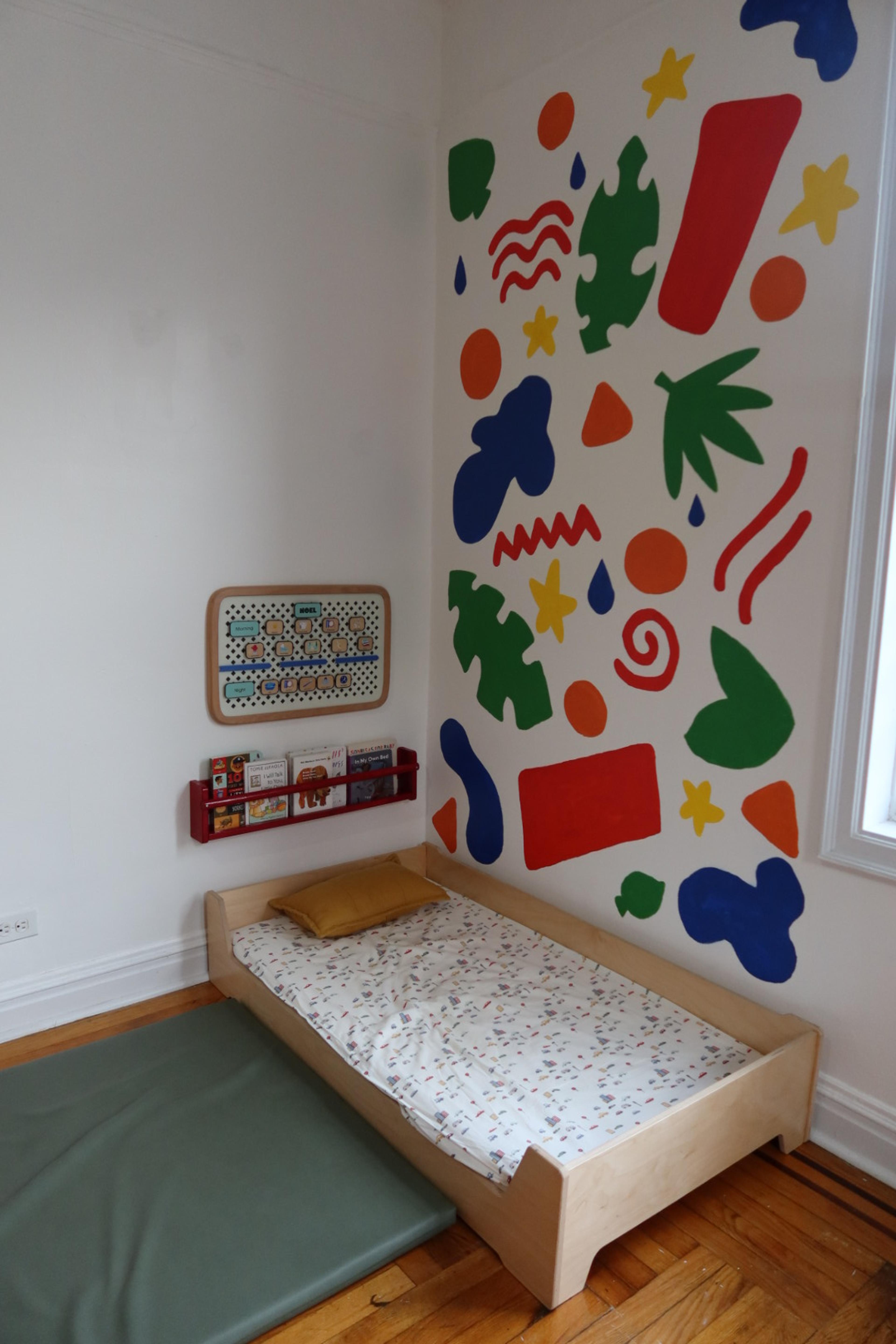 A white crib placed against a color-blocked painted wall section in a primary bedroom.