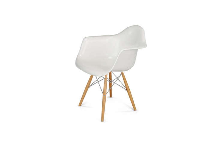 A white fiberglass arm shell chair with a wood dowel base.
