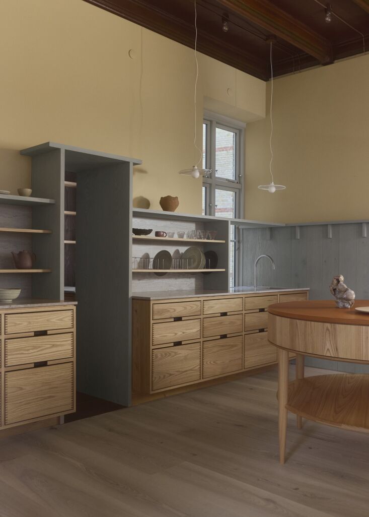 Close-up of a kitchen counter with Portland Taupe Sandstone backsplash and a minimalist John Pawson for Cocoon faucet.