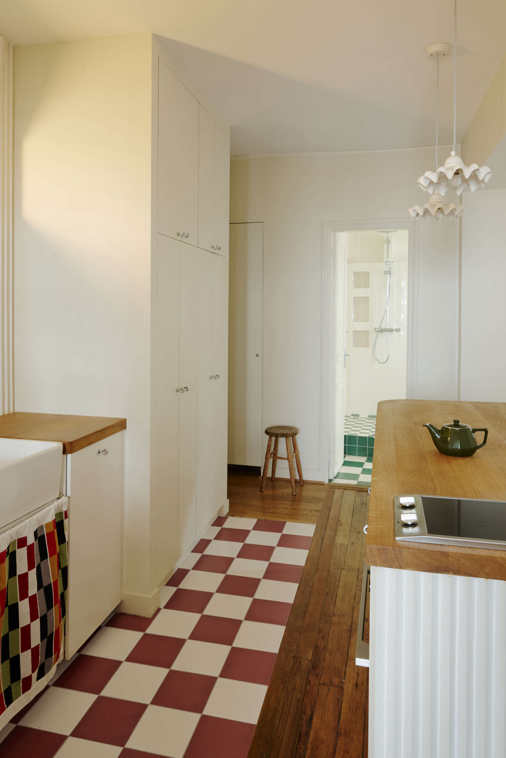 White frilly ceramic pendant lights hanging above a wooden kitchen island in a Parisian-style kitchen.