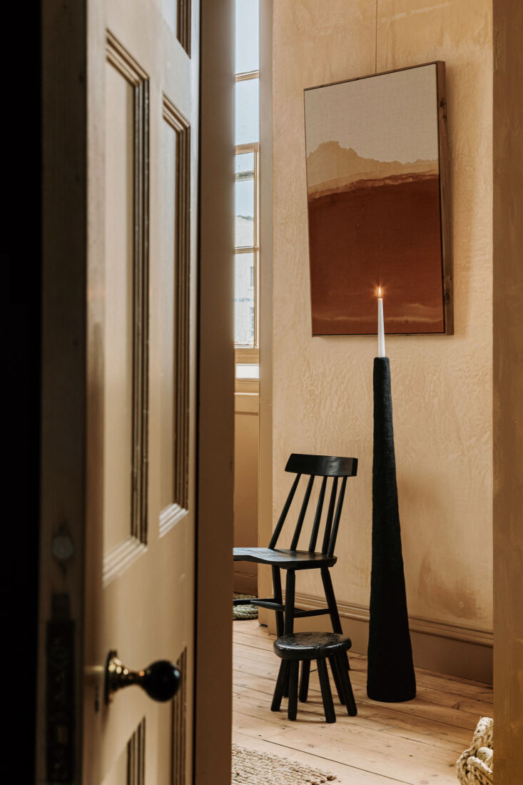 A linen textile piece by Hayley McCrirrick hanging above a wooden vernacular chair.