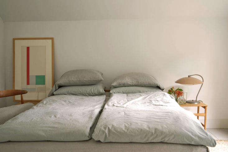 Two twin beds pushed together with separate light gray duvets in a minimalist room.