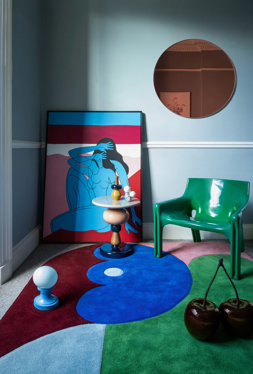 Modern interior featuring a blue and red abstract rug paired with a green chair and colorful wall art.