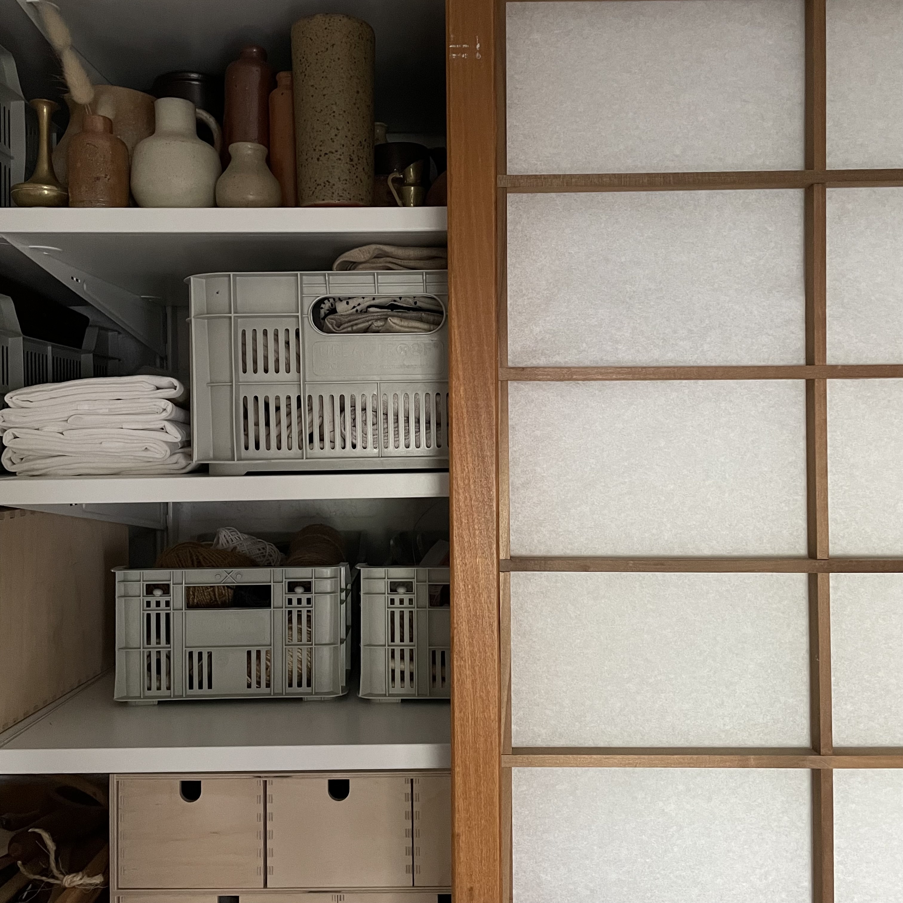 A sliding rice paper shoji screen partially covering storage shelves filled with boxes.