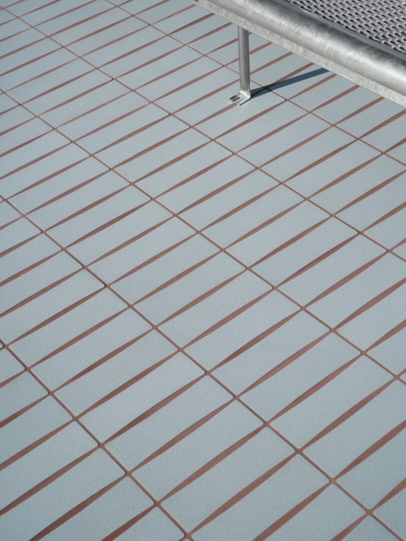 A blue tiled floor with prominent brown grout lines and a metal bench.