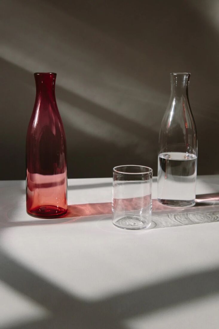Hand-blown glass carafes and tumblers by Lindean Mill Glass displayed on a shelf.
